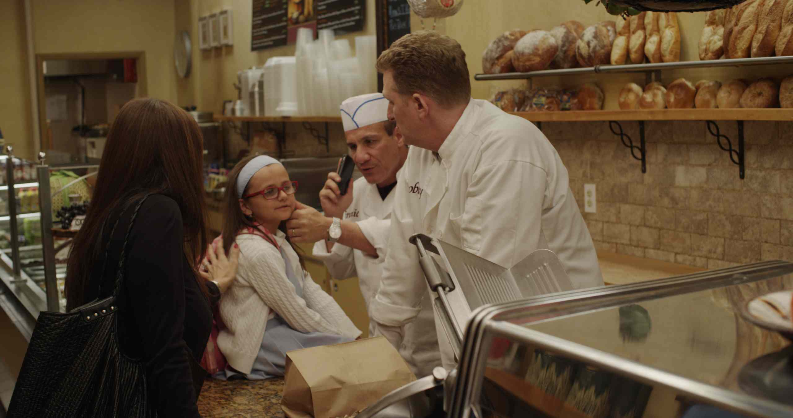 Olivia during a scene at a Middle Village deli with actor Michael Rapaport (far right).