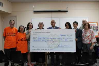 Councilman Paul Vallone and library supporters hold up an over sized check for the amount allocated for library improvements.