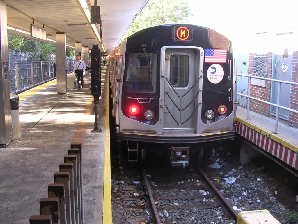 An M train at the Middle Village-Metropolitan Avenue station. (photo via Wikimedia Commons)