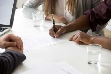 Interracial couple signing financial contract or prenuptial agreement concept, closeup