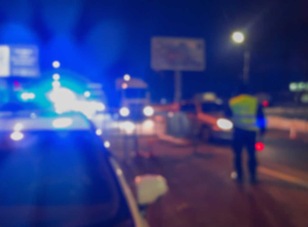 Unrecognizable blurry police car lights and police force officer on night road background, crime scene, night patrolling the city. Abstract  defocused image.