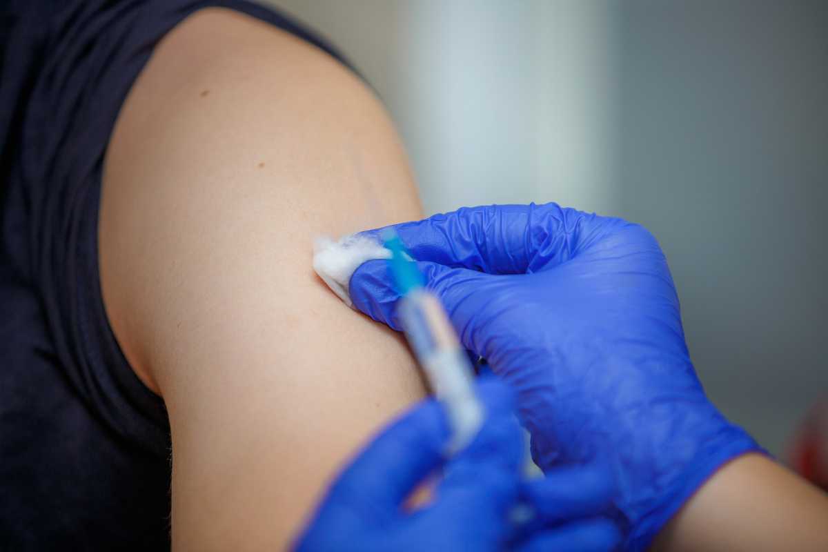 Syringe with medicine in the hands of a doctor in blue gloves.