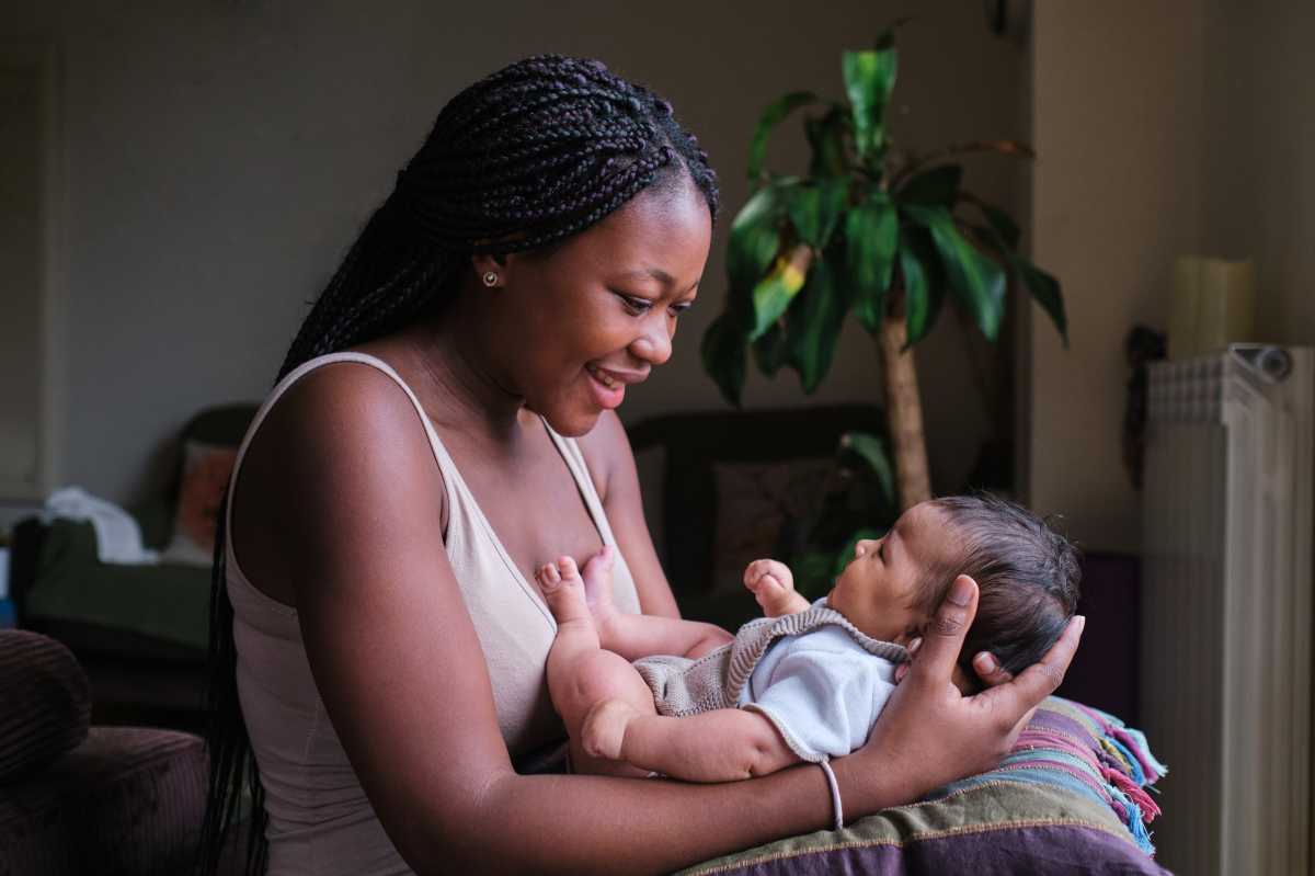 Happy african mother with her baby on arms at home