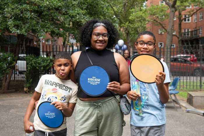 Parent/guardian Shian Simms along with her children who participate in the Save for College Program enjoying Woodside Houses’ Family Day and celebrating the new investment from the Rise Light & Power Community Scholarship 2025 (July 19, 2025). Photo by Bridget Ye for NYC Kids RISE.
