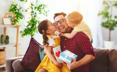Happy father’s day! Children congratulates dad and gives him gift and postcard