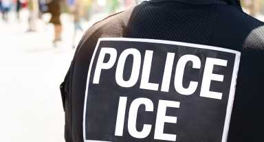 Ice Police Immigration and Customs Enforcement – Close-up of POLICE ICE marking on the back of a hi-visibility stab proof vest worn by a police officer at the scene of an incident.
